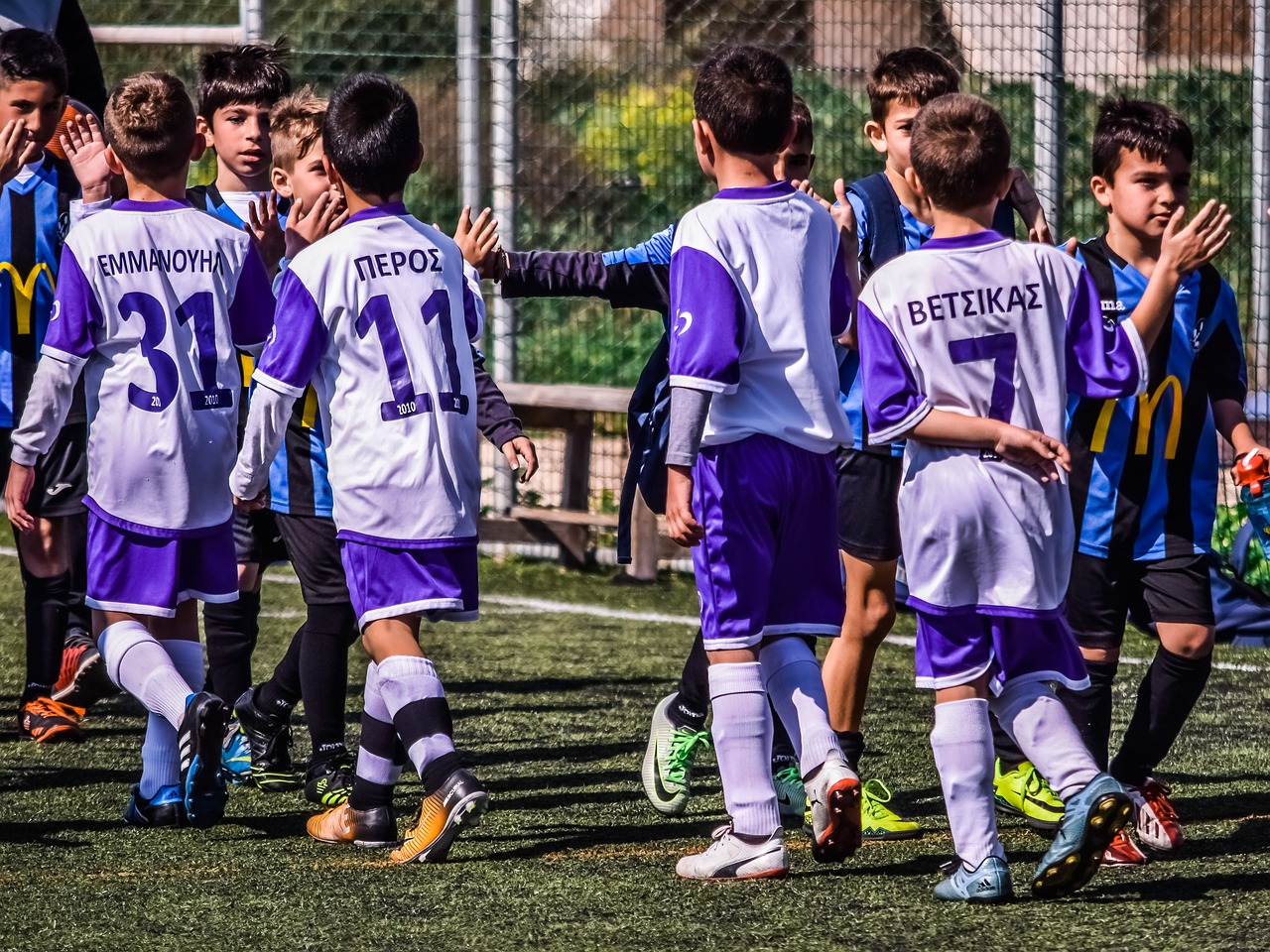 Jovens jogadores de futebol apertam as mãos do adversário na entrada do gramado