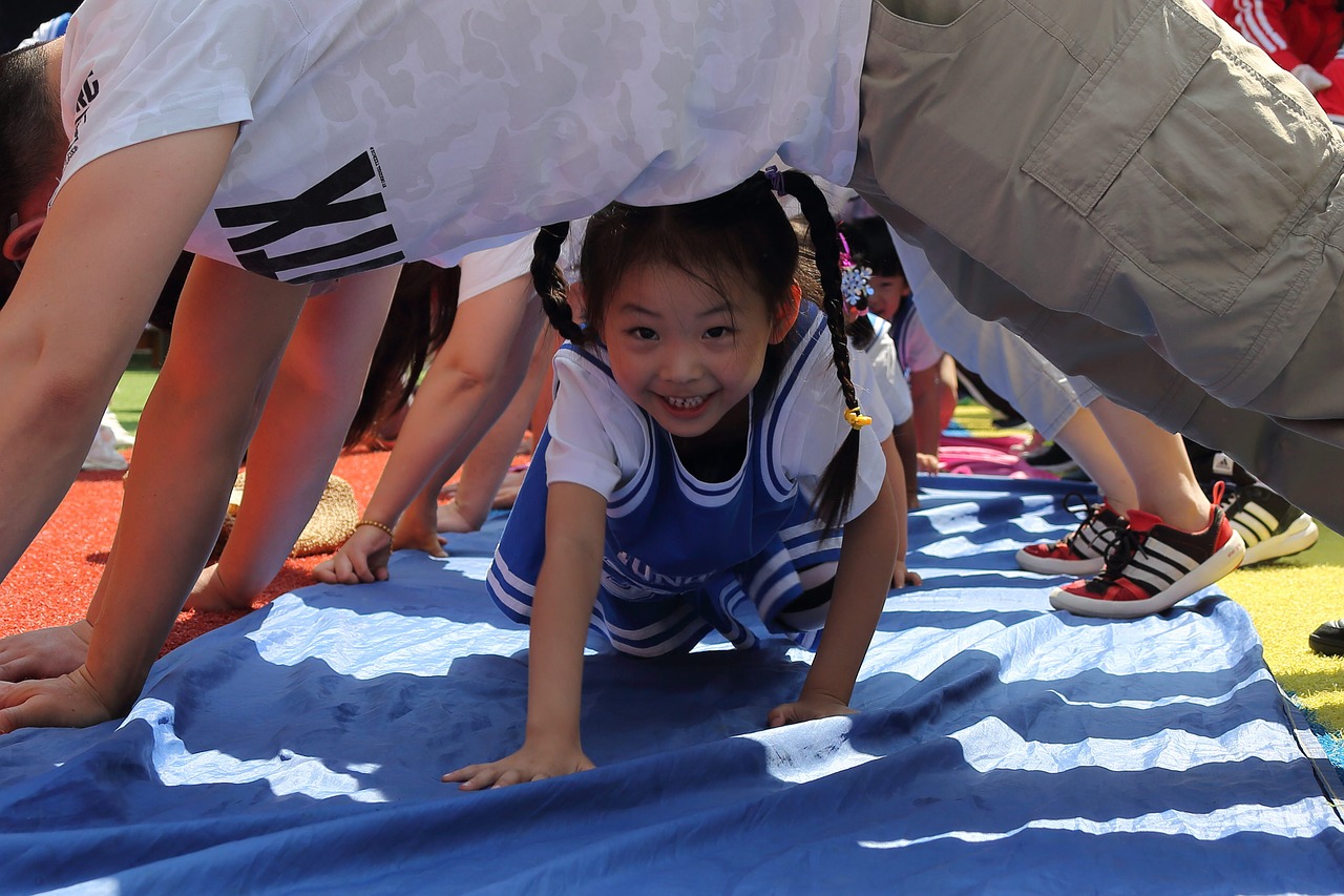 Pequena criança asiática engatinha sorrindo por baixo de adultos apoiados em forma de arco