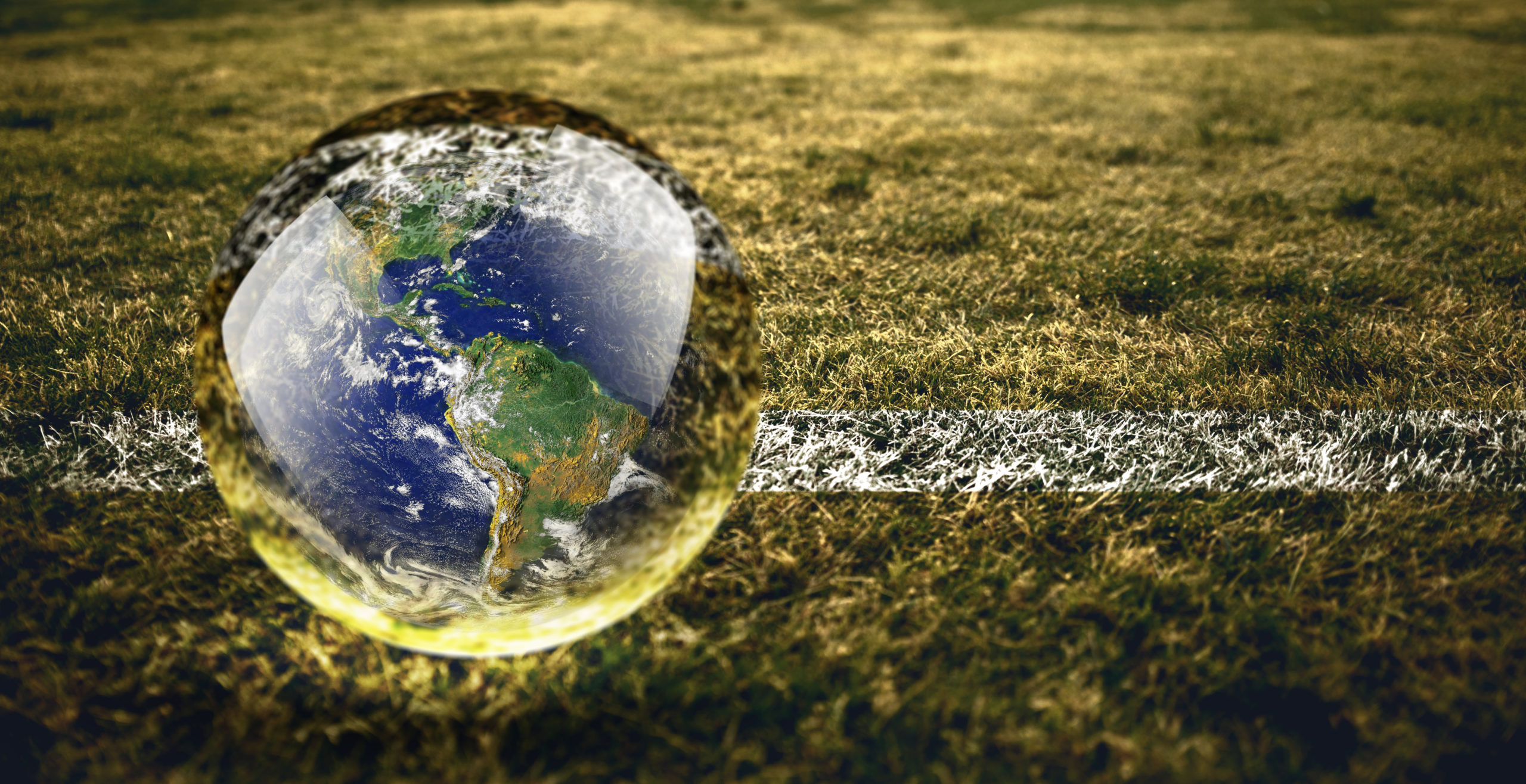 Bola com o desenho do planeta em um campo de futebol
